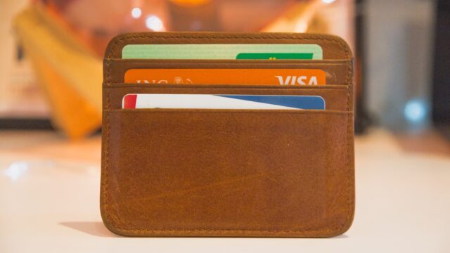 茶色の革製カードケースに複数枚のクレジットカードが差さっている様子。カード審査・所有をイメージした写真