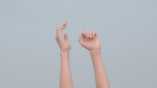 灰色の背景に向かって伸ばされた両手の写真