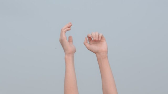 灰色の背景に向かって伸ばされた両手の写真