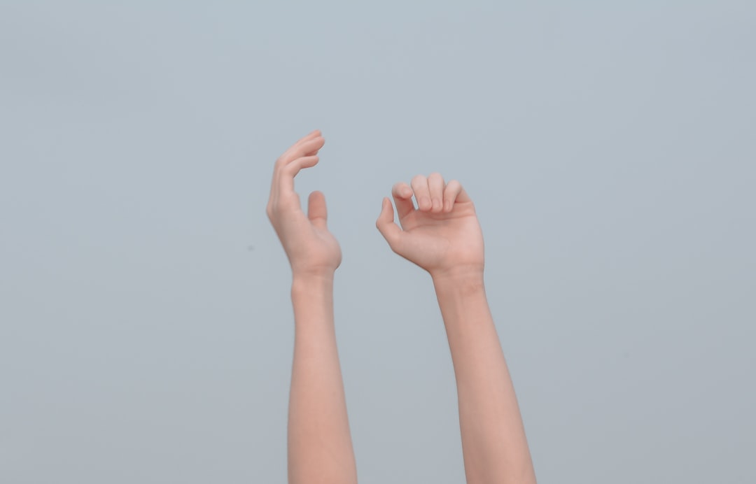 灰色の背景に向かって伸ばされた両手の写真
