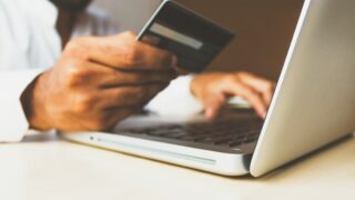 クレジットカードを持つビジネスパーソン。楽天カード決済によるポイントアップキャンペーンを表すイメージ
