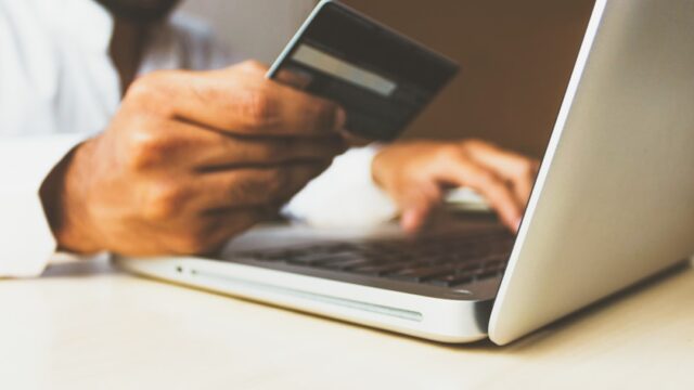クレジットカードを持つビジネスパーソン。楽天カード決済によるポイントアップキャンペーンを表すイメージ