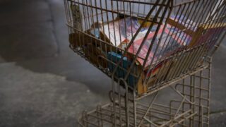 古いショッピングカートに雑多な本が詰め込まれている様子。無駄な買い物・買いすぎのイメージ写真
